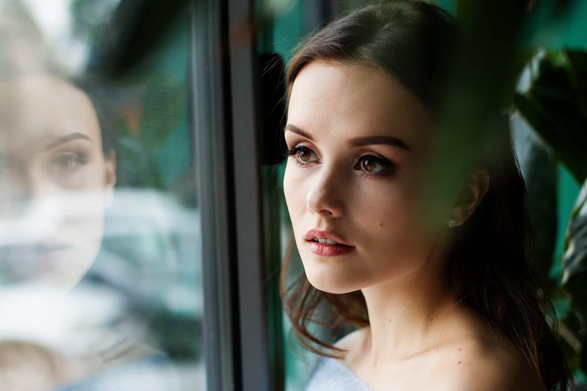 Jeune femme brune qui regarde par la fenêtre